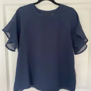 Marinblå t-shirt med volang på ärmarna, i ett tunt material, bra till sommaren. 
