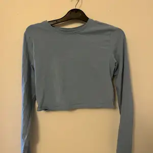 Blå långärmad tröja som är ganska kort
