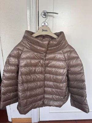 Herno jacka - Säljer Herno ”Sofia” jacka , beige i lättviktsdun, stl fransk 46:a,  likvärdig svensk stl 38. Fint skick.  Resegarderob+ galge medföljer. Tagen medföljer även.