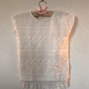 Kortärmad spets  - Fin kortärmad T-skirt med spets på framsidan. Använd men i ganska bra skick. Storleken 122/128. 