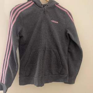 Zip hoodie från adidas. Mycket bra skick men snöret fattas. Grå med rosa tryck.