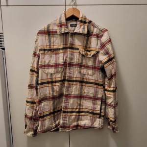 Flanellskjorta/Jacka (M) Dressman - Flanellskjorta från Dressman, knappt använda då jag glömde bort att jag hade den. Säljes då jag har annan klädsmak. Den har fickor vid midjan och tyget är tjockare så den fungerar även som jacka när det blir lite varmare.