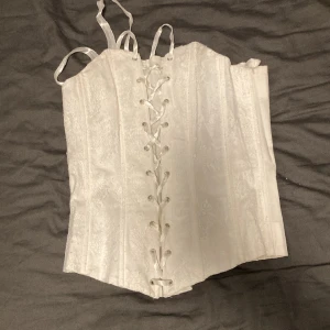 Vit korsett - Vit korsett med snörningen fram. Säljer då den är för stor för mig. Vet inte vilket märket är men jag köpte den för 150kr på myrorna. 
