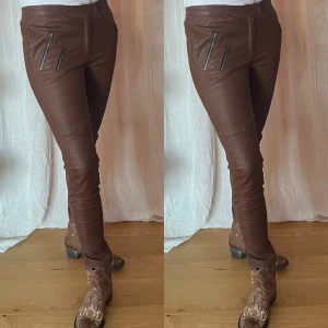 Rabens Saloner skinnbyxor Chestnut  - Oanvända stretchiga skinnbyxor från Rabens Saloner/ Dorita i Chestnut. Gylf och tryckknapp, fickor vid sidorna, inga fickor bak och dragkedjor nertill på byxbenen. Byxan sitter relativt lågt. Sydda i Portugal. Nypris: 6000kr