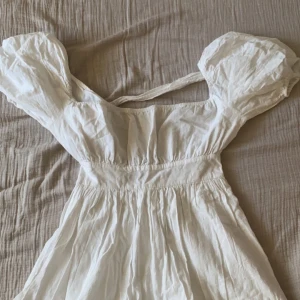 Vit studentklänning  - Vit studentklänning med öppen rygg och puffiga armar. Perfekt till studenten!