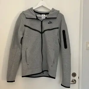 En grå Tech fleece. Knappt använd, tröjan är som ny. Säljer för att den inte kommer till användning ❤️ Tröjan är i storlek XS, priset kan absolut diskuteras❤️Köpte den för 1500kr, säljer för 710