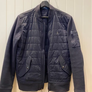 Ralph Lauren Övergångsjacka - Nu säljer jag den här riktigt stilrena Ralph Lauren jackan. Den passar perfekt nu till hösten och är i ett riktigt bra skick, endast använd fåtal gånger. Skicket är 9/10. Och nypriset ligger på 2500kr.   Tveka inte att höra av er vid frågor!