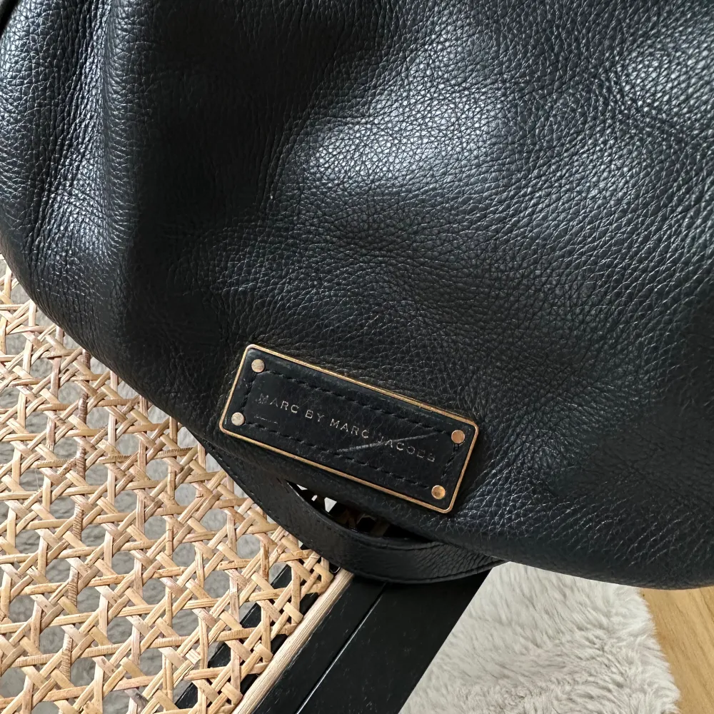 Säljer snygg väska från Marc By Marc Jacobs i svart skinn med gulddetaljer. Det finns två olika handtag varav de ena går att justera längd på. Väskan är i väldigt bra skick. Saknas dock en liten guldknapp på ena sidan (se bild). I övrigt få repor. . Väskor.