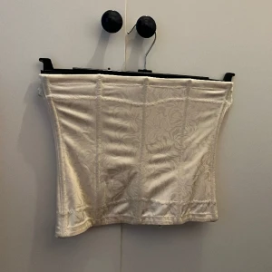 Korsettopp - Korsett topp i vit/beige med ett blommigt möster i strl M men känns som en S 