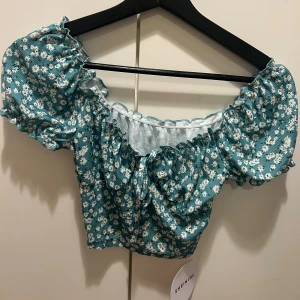 Blommig topp - Helt oanvänd. Prislapp finns kvar. 