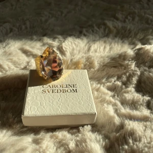 Caroline svedbom ring - Så vacker caroline svedbom ring i jättebra skick. Som ny.  Det är den stora stenen. Ringen är justerbar. Äkta kristaller. Guld. Orginalpris är: 895kr