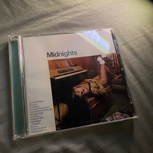 Midnights CD - Säljer en CD-skiva av albumet 'Midnights' från Republic Records. Albumet innehåller låtar som 'Lavender Haze', 'Maroon', 'Anti-Hero', 'Snow On The Beach', 'You're On Your Own, Kid', 'Midnight Rain', 'Question...?', 'Vigilante Shit', 'Bejeweled', 'Labyrinth', 'Karma', 'Sweet Nothing' och 'Mastermind'. CD-fodralet har en bild på framsidan av en person som ligger på en soffa och baksidan visar en närbild av samma person. Inuti finns en bild på personen och själva CD-skivan som har en klockdesign (det finns 4 olika, när man har alla har man en hel klocka) 