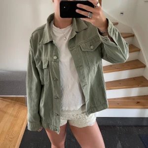 Grön overshirt i manchester - Säljer en snygg grön overshirt i manchester. Den har en avslappnad passform och är perfekt för lager-på-lager-stil. Jackan har långa ärmar, knappar framtill och två bröstfickor med lock. Perfekt för vår och höst! Jackan har lite lösa knappar och var det när jag köpte den men dom har aldrig ramlat av sen jag köpte den för ca 3/4 år sen