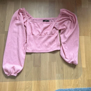 Rosa ribbad topp från Shein - Säljer en superfin rosa ribbad topp från Bik Bok. Den har långa puffärmar och en fyrkantig halsringning. Toppen är croppad och perfekt för både vardag och fest. Den är i nyskick och väldigt bekväm att ha på sig. Passar perfekt till ett par höga jeans eller en kjol!