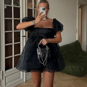HELT NY  Lojsan Wallin organza svartklänning strl 38 - Oanvänd organzakänning fr NA-KD, strl M. Klänningen har en pösig look. Den har en minilängd och puffärmar i mesh, en bustier med en inre silikonkant, en stretchig hälrem, en underkjol i tyll och ett knytbart band på baksidan. Nypris: 800 sek