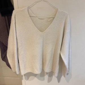 Krämvit stickad tröja - Stickad tröja i en fin krämvit färg. Väldigt fin och stilren. Den är B-ringad i en kort modell runt midjan.   Köpt på Sellpy! 