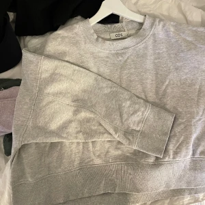 Grå COS sweater - Grå sweater från cos i nyskick, lite kortare och bredare modell, snyggt oversized, storlek M