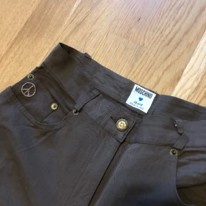 Moschino Jeans byxor - Favoritbyxorna från Moschino Jeans. Inköpta på Humana Secondhand, använda en gång. Säljes pga hade velat ha de längre (jag är 168). Färgen är en fin olivbrun. Jättefint skick. Storlek: I44/US10/F40/GB14/D40 enligt lapp. Uppskattar som en XS/S ✨