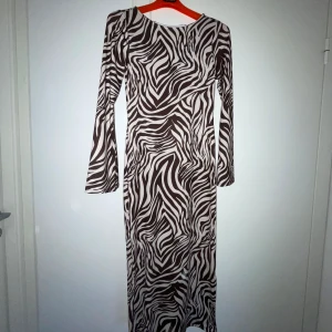 Lång figurnära klänning - Figurnära zebramönstrad klänning. Aldrig använd (pga fel storlek), har fortfarande prislapp.  Mycket trendig, väldigt snygg klänning med zebramönster🦓. Köpt för 500 kr 