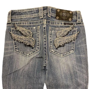 Low Waist Bootcut Miss Me Jeans - Ett par low waist bootcut Miss Me jeans i storlek 27. Jeansen är i fint skick med inga skador eller fläckar. Mått: Längd: 105 cm, Midja: 38 cm tvärs över och Innerben: 78 cm. Vid fler frågor tveka inte att kontakta oss!