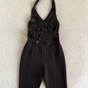 ZARA jumpsuit med paljettväst / korsettväst - OTROLIGT snygg jumpsuit från ZARAs festive collection med en halterneck paljettväst insydd med ett par kostymbyxor. Paljettvästen stängs fram med hakar som en korsett. Ny med tags. Har någon liten tråddraggning på byxorna men inget som stör. 🌻