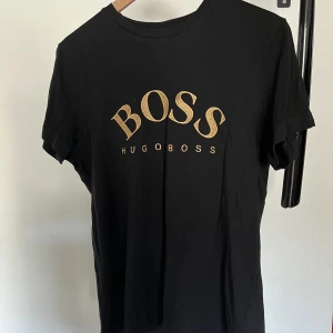 Hugo Boss T-shirt  - Äkta svart Hugo boss T-shirt i bra skick med sydd text , perfekt för sommaren.