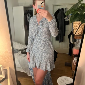 Blå klänning - Säljer min blåa klänning med viat blommor då det inte kommer till användning längre, den är i fint skick och man kan välja storlek lite själv då det är knyte💕skriv vid intresse eller för mer information 