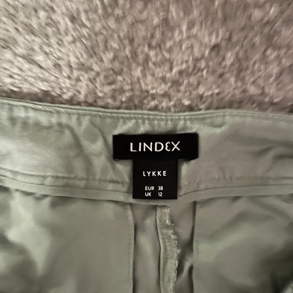 Gröna högmidjade kostymbyxor. Använda fåtal gånger. I storlek 38 från Lindex. Säljes för att de aldrig används. (Skrynkliga på bild för att de legat i garderoben ett tag men lätta att strykas). Jeans & Byxor.