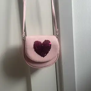 Rosa fin lite handväska med ett hjärta på som kan vara två färger