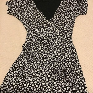 En svart somrig och blommig klänning  - Klänning är köpt i Turkiet och är i bra skicka och använd ca 4 ggr. En perfekt klänning nu inför sommaren.