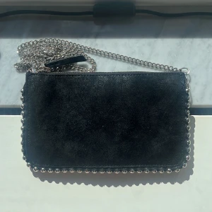 Snygg axelremsväska från Zara - Säljer min trendiga axelremsväska från Zara! Den är svart och skimrar lite i solen😍 Kommer inte till användning, nyskick använd fåtal ggr 