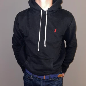 Ralph lauren hoodie - Säljer en Ralph lauren hoodie i riktigt fint skick! Använd typ 5 gånger o är storlek XS. Den är svart me ett rött märke. Vita snören finns på. Skick: 9,5/10. Modellen är 170 o väger 52.