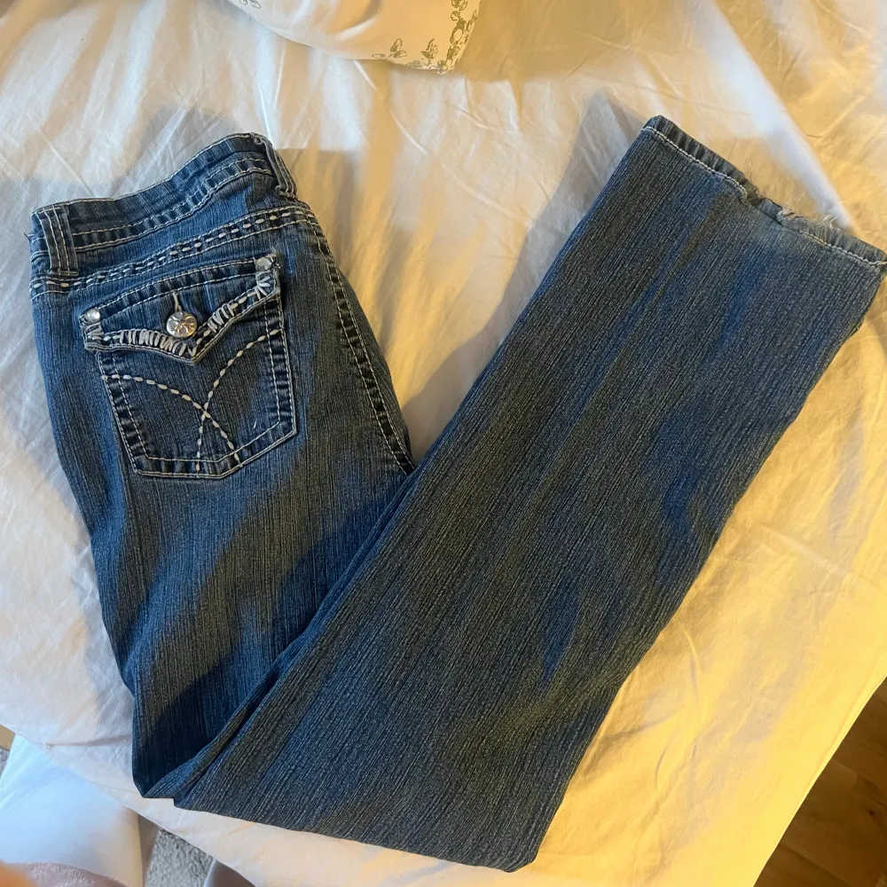 Supertrendiga jeans. Lågmidjade med häftiga fickor och kontrast-sömmar.  Väldigt häftiga, fin tvätt.    En Sten har lossnat på knappen på ena bakfickan  Storlek motsvarar 36-38. Jeans & Byxor.