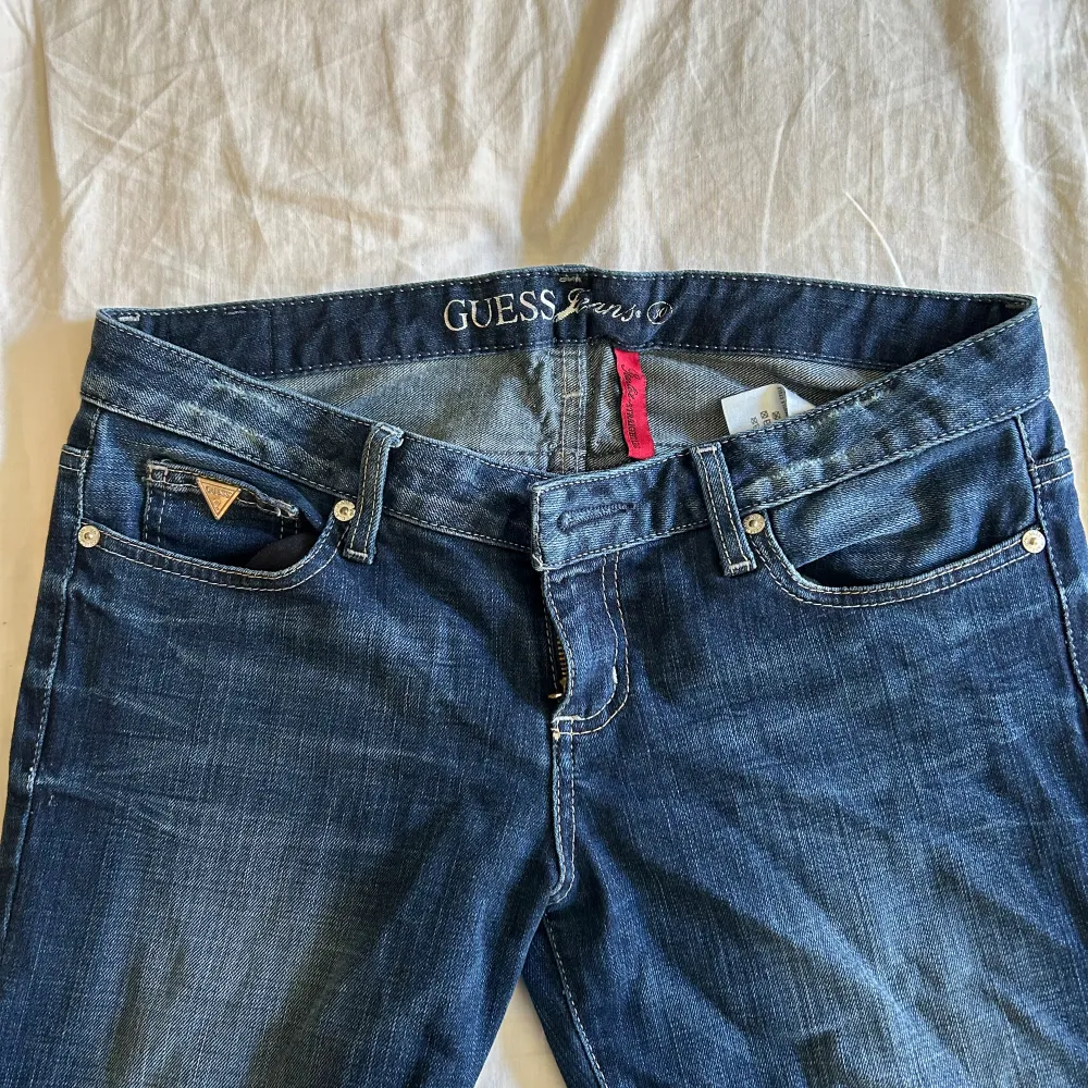 Skit snygga lågmidjade mörkblåa Guess jeans som inte kommer till användning. Står w30, och satte väldigt bra på mig i storlek 38. Skit snygga detaljer på fickorna och framsidan. Innerbenslängden: ca 81-82cm Midjemått: 30w (enligt lappen). Jeans & Byxor.