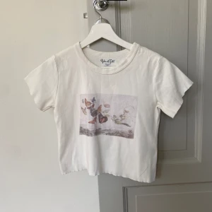 Brandy Melville baby tee  - Vit Brandy Melville baby-tee med tryck. Helt slutsålt överallt. Använd, perfekt skick 