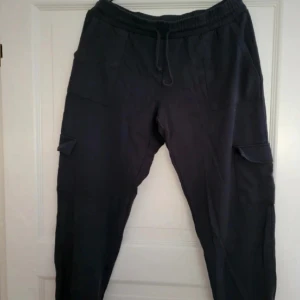 Cargobyxor  - Svarta cargobyxor, lågmidjade. Står 40/42 men sitter som 38 och är korta i benen