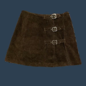 Brun Manchester Kjol - Brun manchester likande tyg  Storlek 42 men är liten i storleken  Längd 39 cm Midja 32 cm Går att öppna hela vägen 