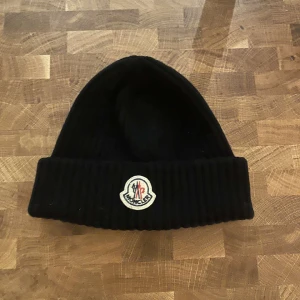 Moncler mössa - Hej säljer denna snygga moncler mössan som jag knappast använt, den är i nyskick och inte en skada, hör av dig vid frågor!
