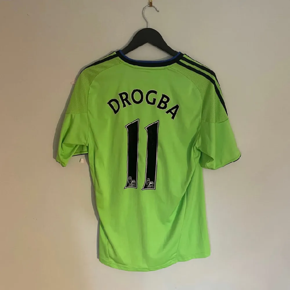 Chelseas officiella tredjetröja från 2010 med Chelsea legenden Drogba #11 på ryggen. Tröjan är i grymt skick utöver en missfärgning strax under Samsung sponsorn.   Produktkod P00189. T-shirts.