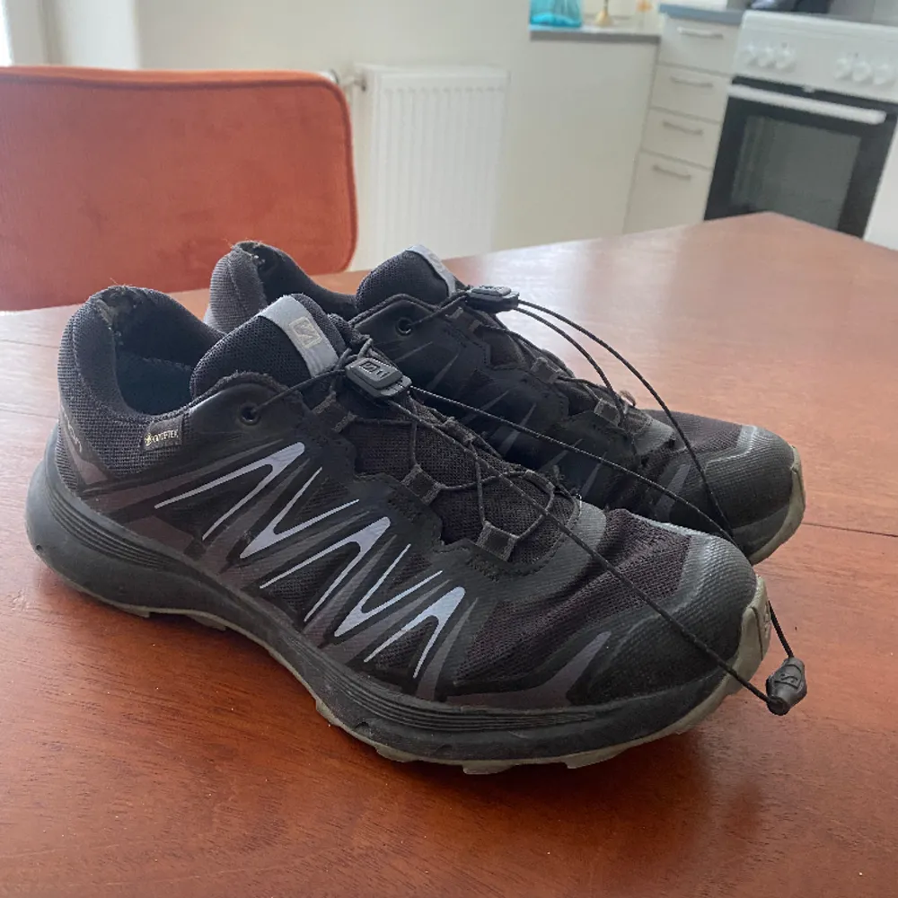 Svarta Salomon sneakers, skorna har lite slitningar och saknar original sula därav det låga priset!  Storlek 38,5  Kan mötas i Stockholm eller frakta . Skor.