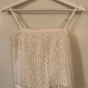 Somrig croppad topp i spets från Hollister  - Använd 1 gång, i mycket fint skick. Storlek XS, normal i storleken.  Justerbara tunna axelband. Något croppad