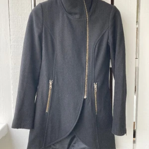 Jättesnygg figurnära jacka - Jättesnygg figurnära vinter/vår/höst-jacka. Från Gestuz. Storlek 36, svart med svart foder. Två fickor med dragkedja framtill. Dragkedjor nedtill på ärmarna, som går att öppna upp.