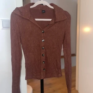 Brun rostfärgad och långärmad tröja med krage  - Långärmad tröja med krage och knappar. Väldigt fin!