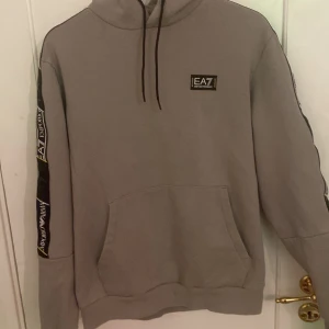 EA7 Hoodie - Säljer denna EA7 pga att den blivit förkort i armarna den är köpt på pondus i Karlstad för ca 1450kr. Skick 8/10 det är bara små fläckar som knappt syns