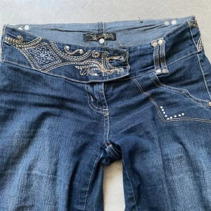 Coola rare super lågmidjade bootcut jeans med stenar diamanter och detaljer utan fickor - Midjemått: 35/36. Innerben: 83 cm. Passar strl S då dom är ganska stretchiga. Inga större defekter men ända är väll att den har lite lösa trådar men det är inget som syns direkt. Annars fint skick och så coola. Säljs då dom är för små. Använd köp nu🤩