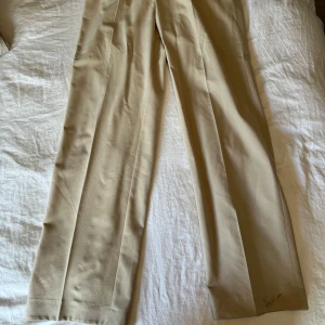 Kostymbyxor oversized - Beiga vida kostymbyxor från weekday i storlek 50.  Har en liten fläck på ena benet. Som borde gå bort i tvättmaskin.