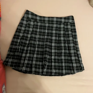 Svart och vit rutig kjol från Bershka - En svart och vit rutig kjol från Stradivarius. Kjolen har ett plisserat mönster och är kort i längden. Den har en dragkedja på sidan för enkel på- och avtagning. Skriv gärna om ni har frågor 💕💕