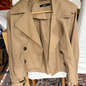 Kort trenchcoat  - Säljer denna korta trenchcoaten, använd 1 gång bara. Köptes förra året, nyskick. 