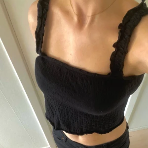 Svart topp - somrig svart topp med fina vågiga detaljer på axelbanden!