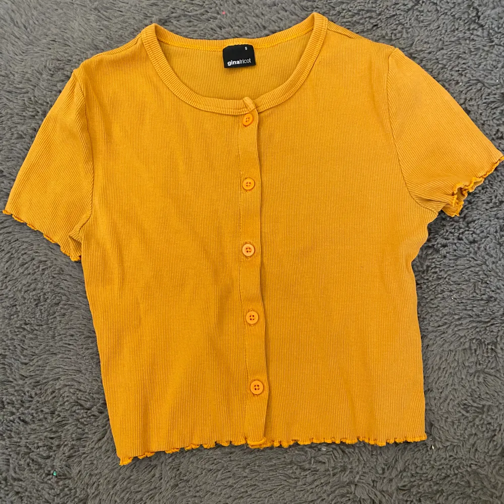 En gul t-shirt med knappar från Gina tricot. Stretchigt material så passar storlek M som en tajt magtröja. Kontakta privat för mått och fler bilder❤️. T-shirts.